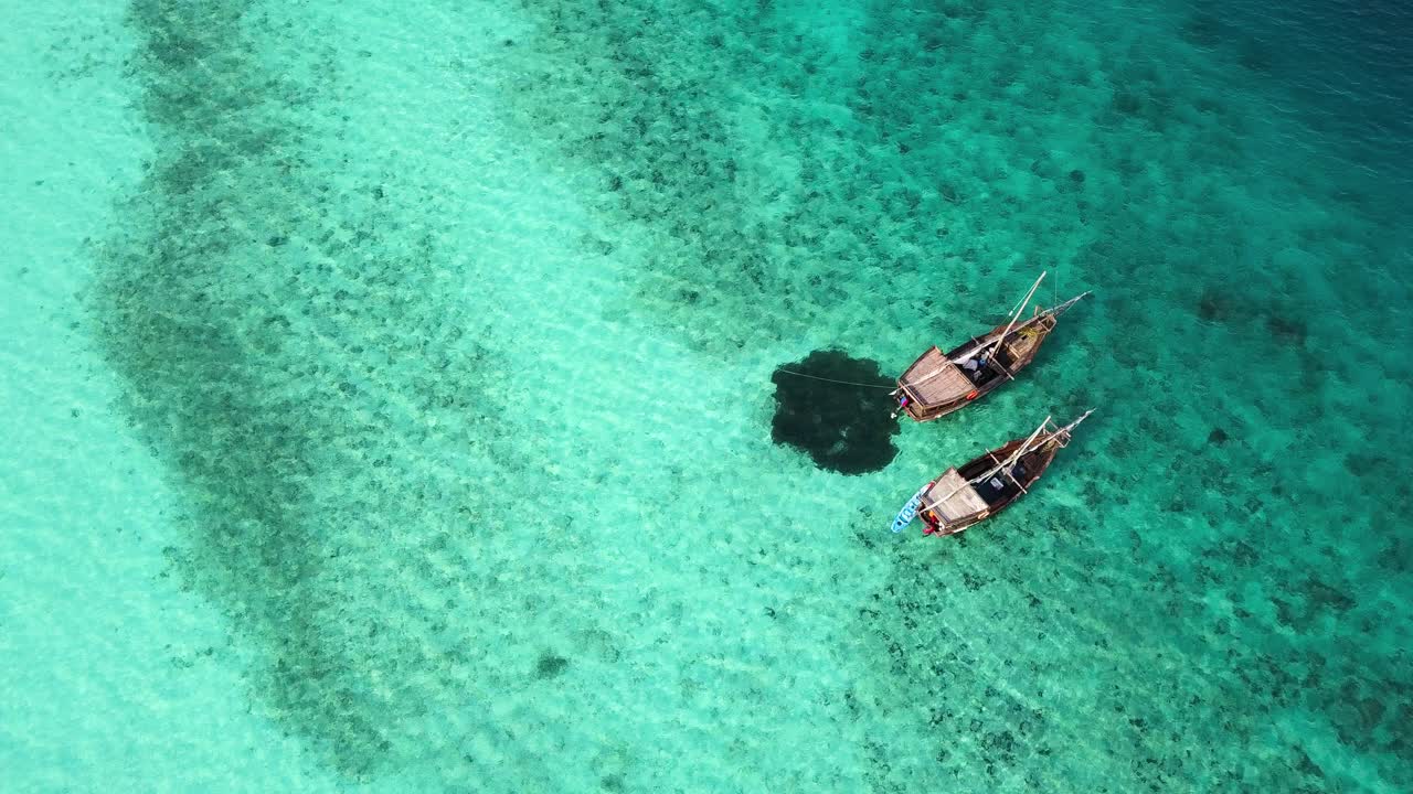Aerial birdseye static shot of two wooden boats anchored off coast of Zanzibar