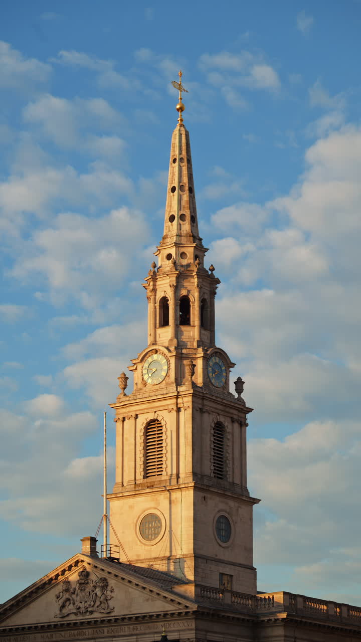 Tall clock tower of the St Martin-in-the-Fields church captured under a partly cloudy sky in London, England. Vertical