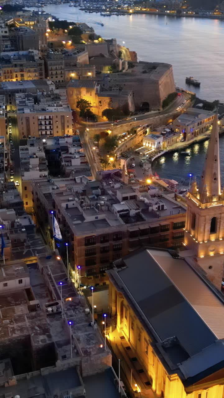 Aerial drone view of the walled city of Valletta, Malta, surrounded by the Mediterranean sea in the evening. Vertical vertical