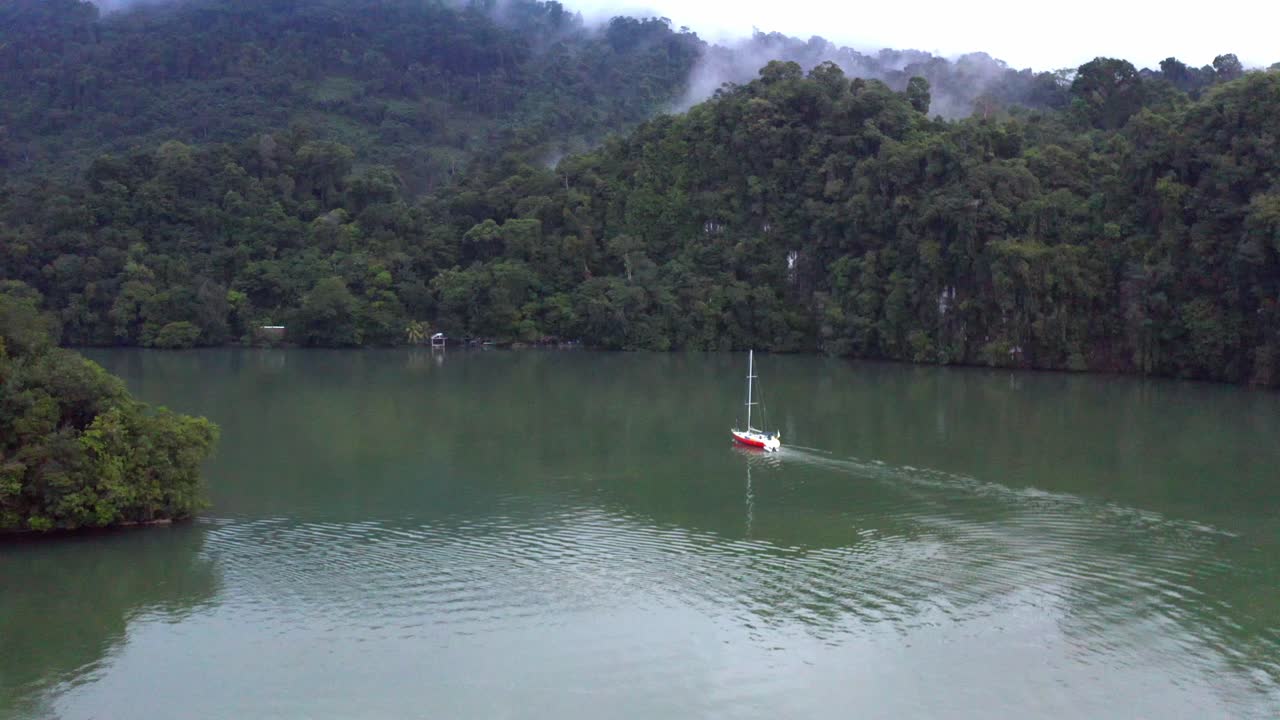 작은 요트는 휘어지는 남미 수로를 우아하게 이동합니다.