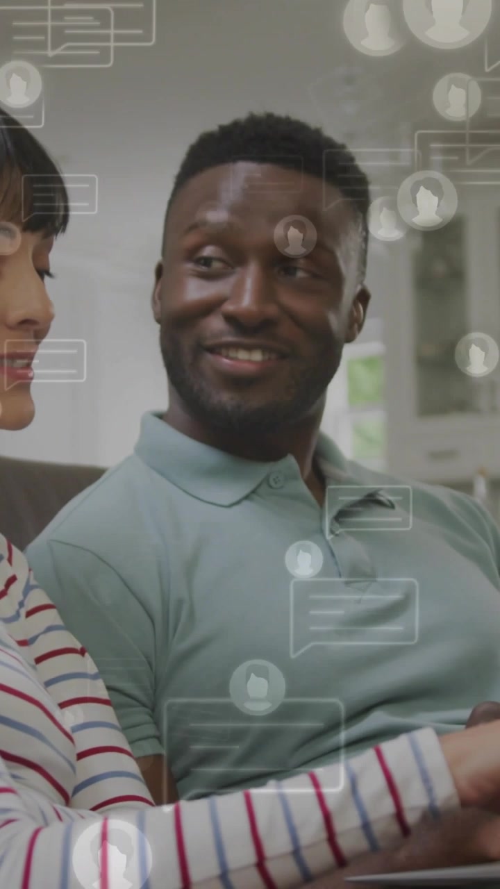 Vertical video: Woman swiping tablet and man smiling on couch launching social chat overlay for fun