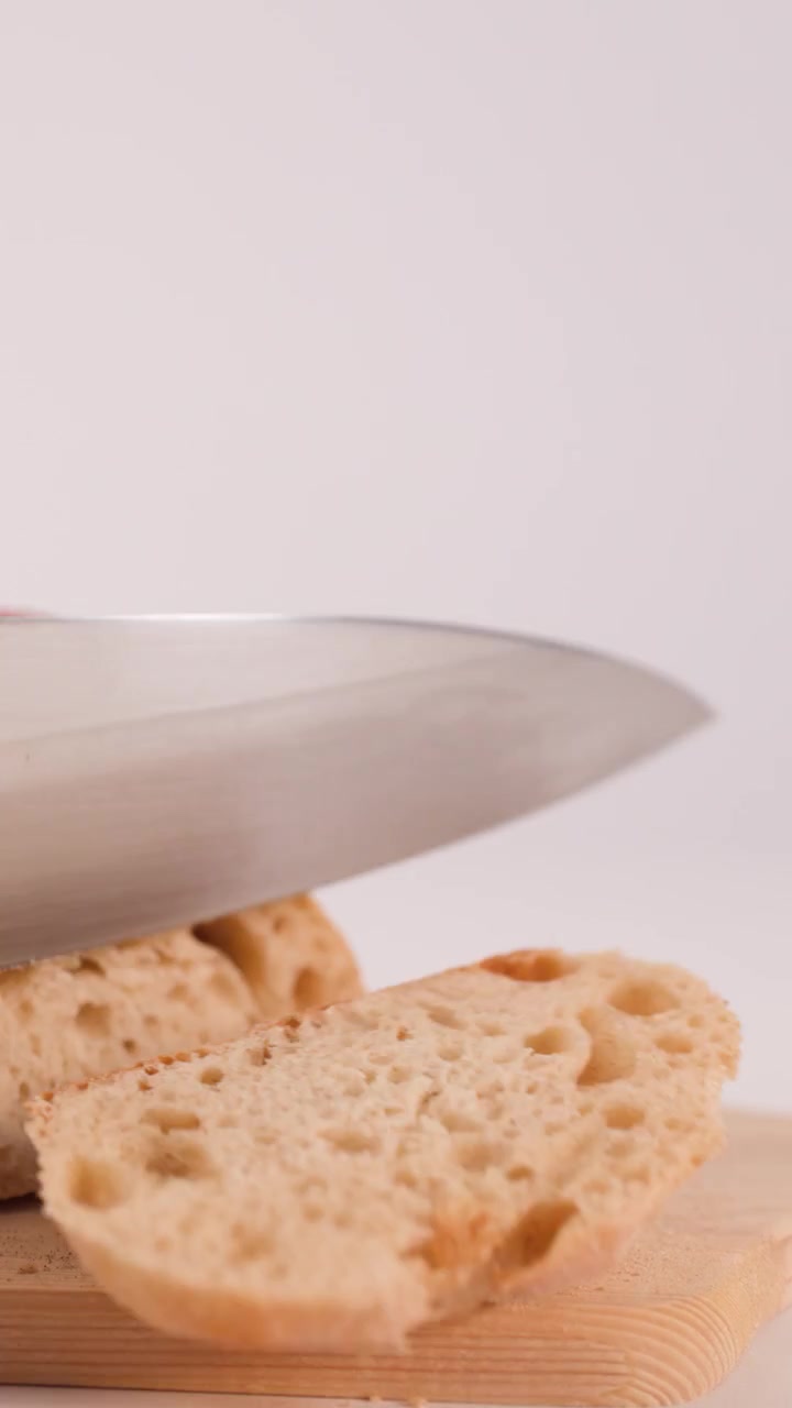 Person Slicing Fresh Crusty Bread on a Wooden Cutting Board