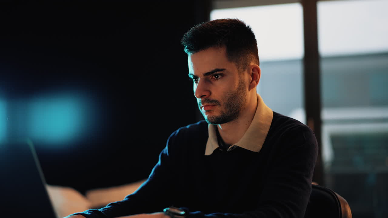 Primo piano di una persona concentrata su un laptop in un ufficio moderno. L'illuminazione ambientale blu crea un'atmosfera calma e tecnologica, adatta per il business, il lavoro digitale e gli stili di vita contemporanei.