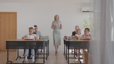 the children in the class are sitting at their desks and the teacher walks around the class and explains the topic of the lesson. smart children learning in friendly modern environment