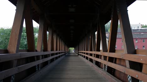 a still interior shot of a beautiful covered bridge with trees and buildings visible through the sides creating a sense of perspective