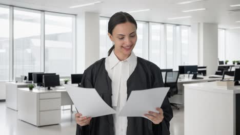 una feliz abogada india leyendo archivos de casos
