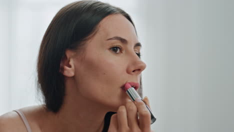 Happy-girl-colouring-lips-looking-mirror-indoors.-Closeup-lady-enjoying-makeup