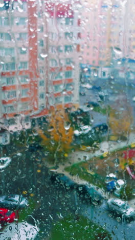 residential area on rainy day from the window on top floor. it's raining outdoors in the city. vertical video