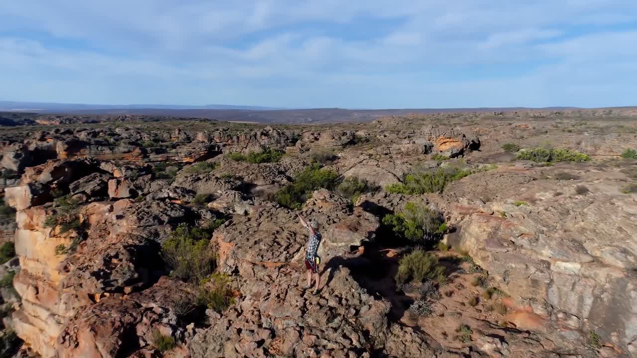 escalador masculino de pie sobre una montaña rocosa 4k