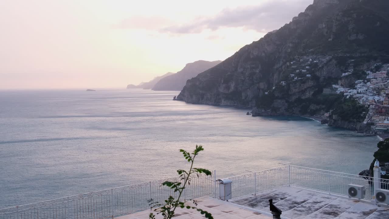 Stunning sunrise view from a terrace over the famous Amalfi Coast in Italy. The sun illuminates the cliffs and the village of white houses perched above the sea