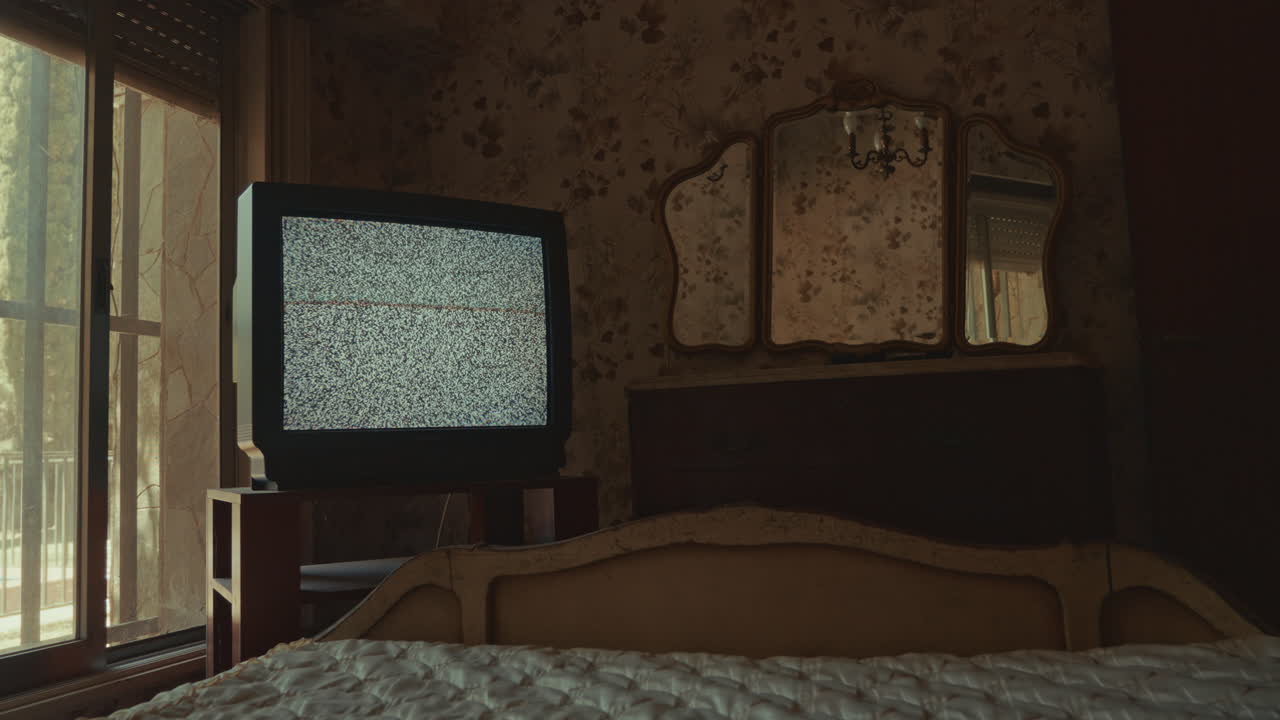 Ancien téléviseur affichant de la neige dans une chambre vintage sombre.