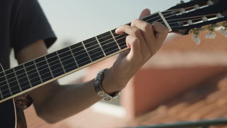 close up of an unrecognizable man keeping hand on guitar fretboard and playing music at party