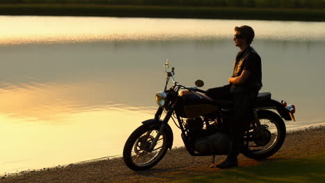 man with motorcycle at sunset by the lake