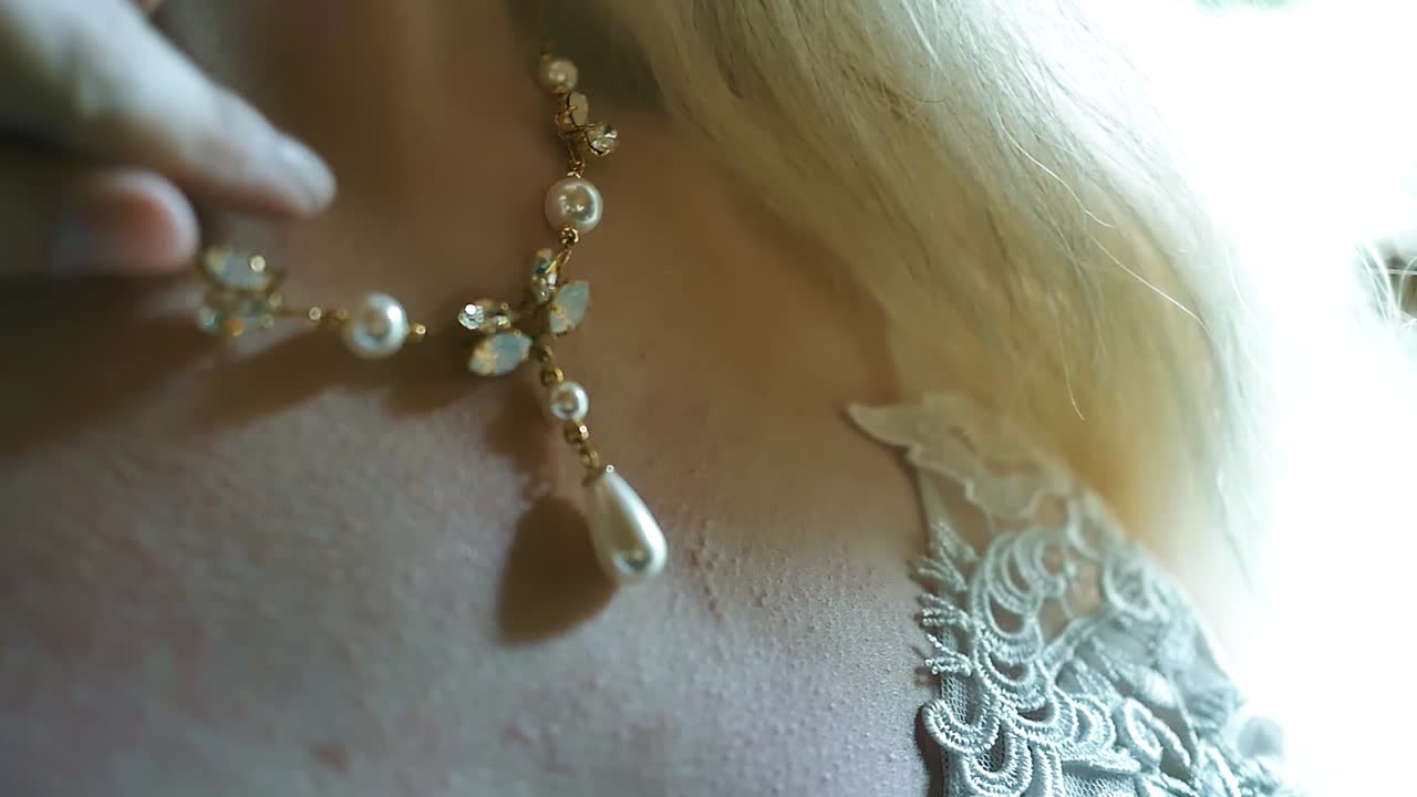 primer plano de la novia ajustando un collar el día de su boda