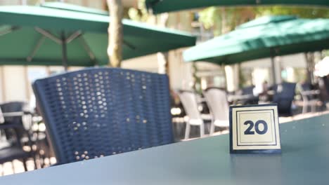 an empty table with a number 20 sign on it at an outdoor cafe.