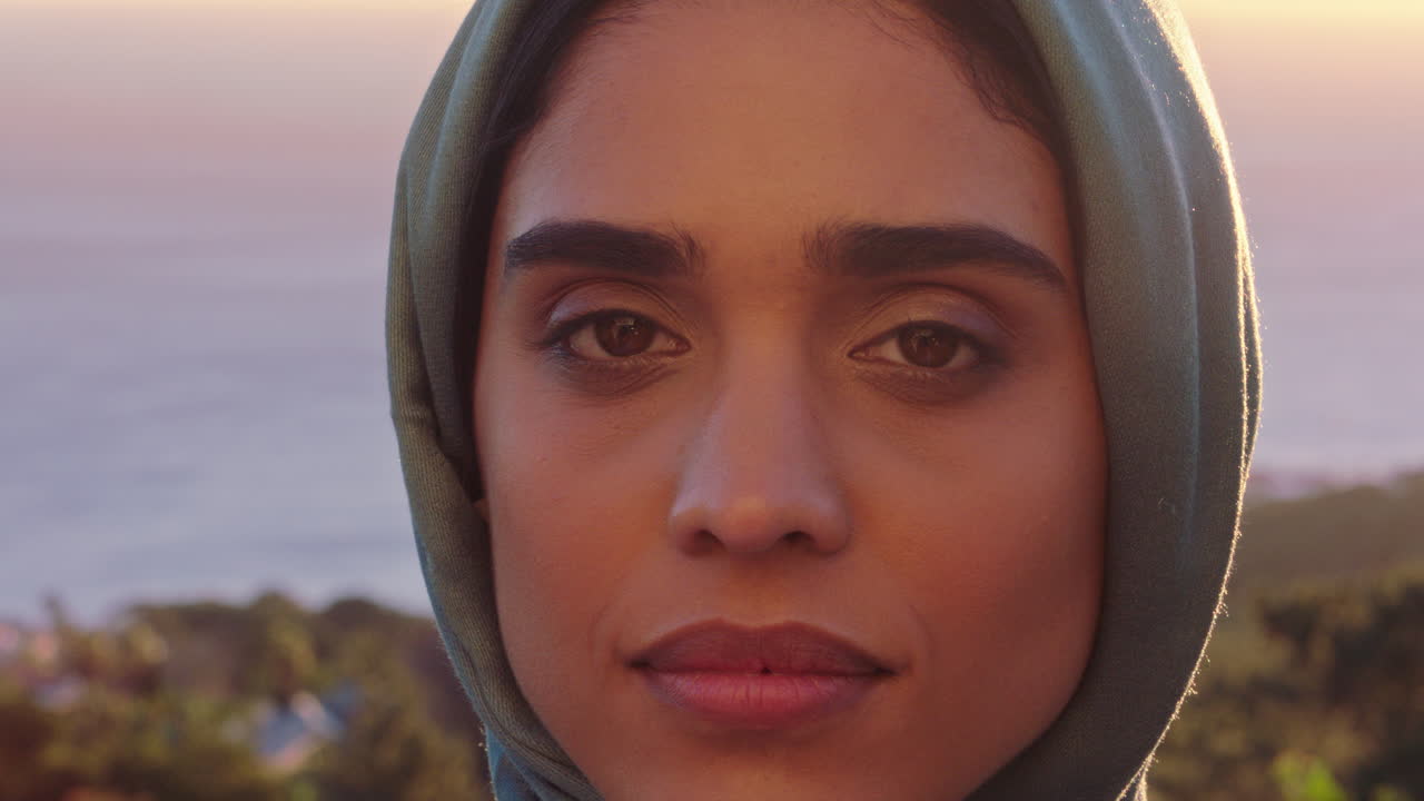 retrato de cerca mujer musulmana atractiva que se ve confiada explorando la espiritualidad disfrutando del atardecer usando un pañuelo de hijab