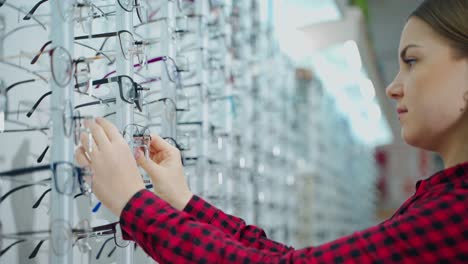 glasses in optical store. young woman choosing fashion eyewear at optical shop