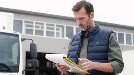 caucasian mature man in front of warehouse with documents.