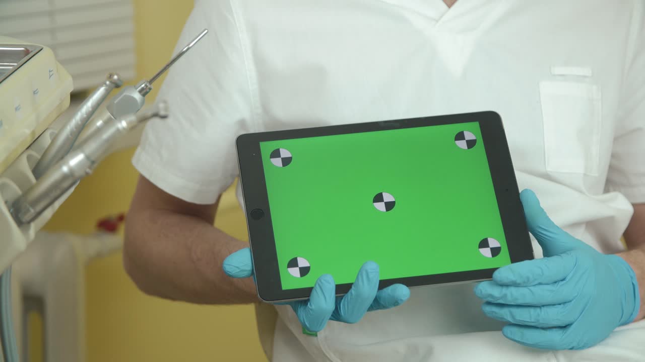 Dentist holding a tablet with a green screen