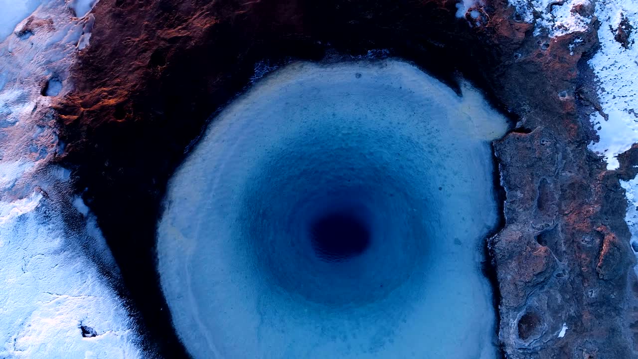 아이슬란드의 게이시르 (geysir) 에 있는 게이저 (geyser) 의 중심을 가까이서 볼 수 있습니다. 이 게이저 밖으로 어나오고 사람들이 해가 지는 곳에서 게이저를 둘러싸고 고 있습니다.