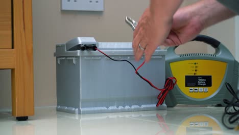 Car-battery-and-charger-being-set-up-and-switched-on-for-charging-a-flat-battery