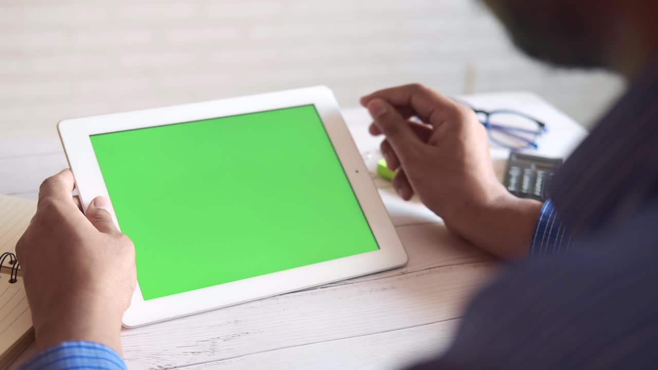 녹색 화면을 가진 태블릿을 사용하는 사람