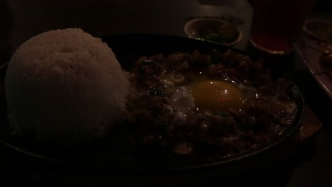 pork sisig is a traditional dish in the philippines served still sizzling with a fresh egg cooking on top of the meat as it sizzles