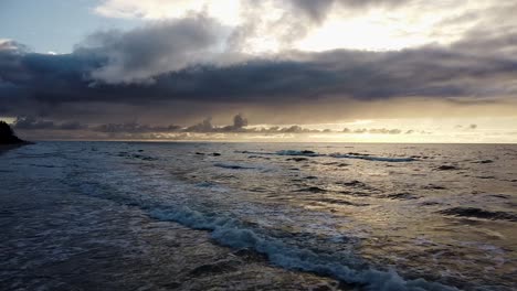 Beautiful-aerial-shot-flying-over-a-beach-at-sunset-on-the-Baltic-sea-coast,-high-contrast,-overcast-weather,-wide-angle-drone-shot-moving-backwards-over-the-sandy-beach