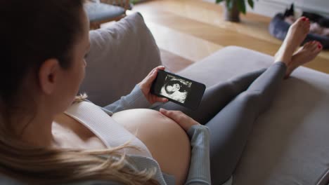 pregnant woman looking on medical scans on the smartphone