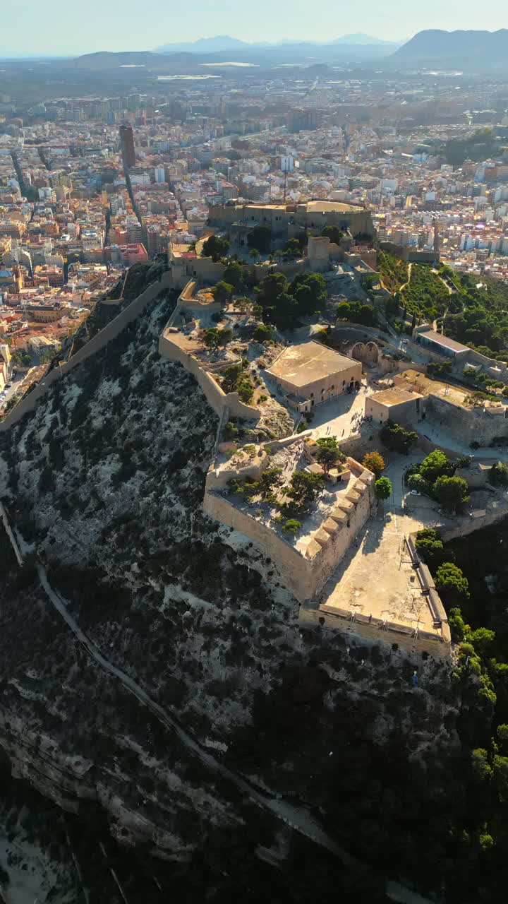 Aerial drone view of the Santa Barbara Castle on the coast of Alicante, Spain with the city on the background. Vertical