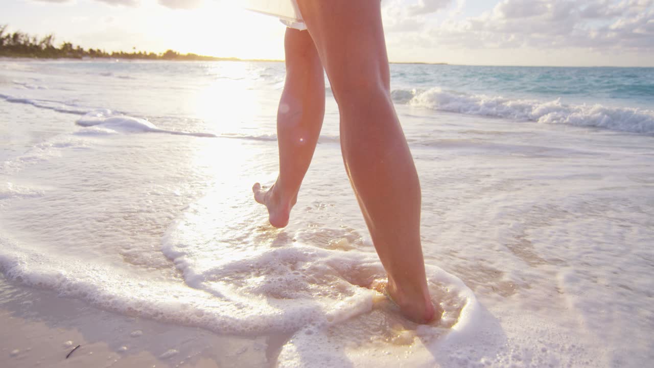 Gambe di donna caucasica a piedi nudi che si gode il tramonto sull'isola.