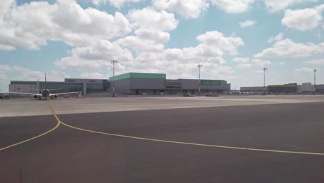 On-a-partly-cloudy-daytime,-the-view-from-the-airplane-window-reveals-Istanbul-Airport,-showcasing-the-Turkish-Cargo-facility,-the-Celebi-ground-handling-building,-and-a-parked-aircraft-nearby