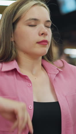 la dama de rosa cierra su portátil en un restaurante ocupado, pareciendo aburrida, inclina la cabeza de un lado a otro, se estira y junta las manos mientras la gente está sentada y hablando a su alrededor