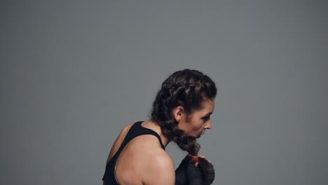 Young-woman-training-with-her-hands-wrapped-in-boxing-tapes-isolated-on-grey-background.-Slow-Motion-shot