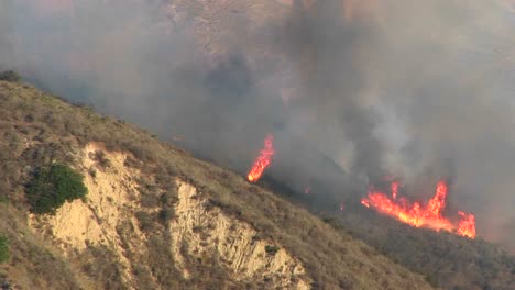 zoomout from wildfires burning on a smoky hillside in southern california