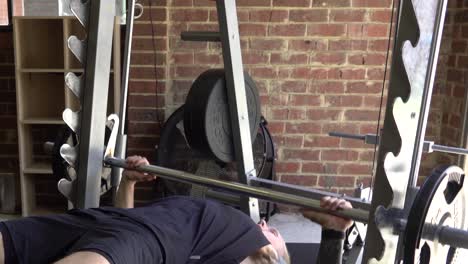 muscly man in home gym exercising decline smith machine bench press