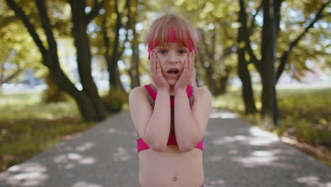 athletic fitness runner girl raising hands in surprise looking at camera shocked by sudden victory