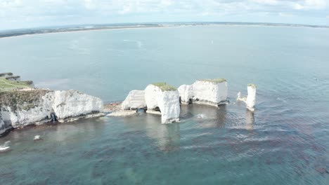 Disparo-Lento-Y-Bajo-De-Un-Dron-Hacia-La-Formación-Rocosa-De-Old-Harry,-Bournemouth,-En-El-Fondo