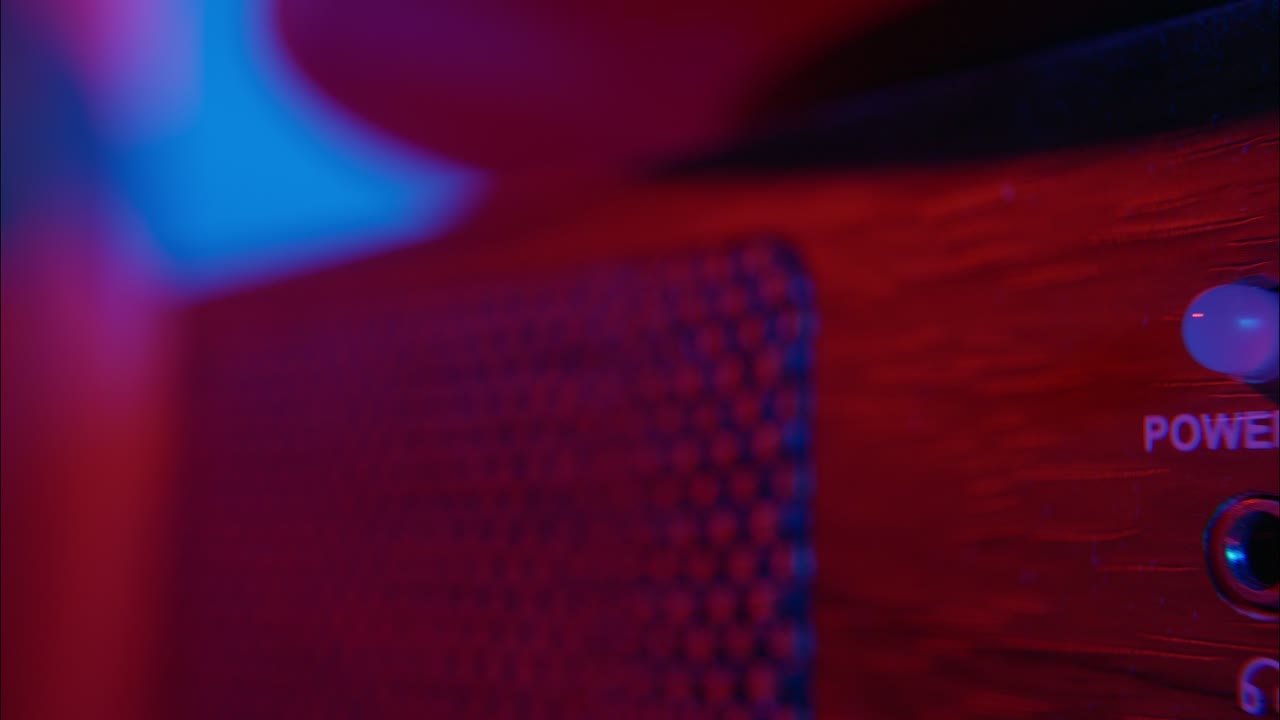 Un dito preme il pulsante di accensione su un dispositivo elettronico con luce verde
