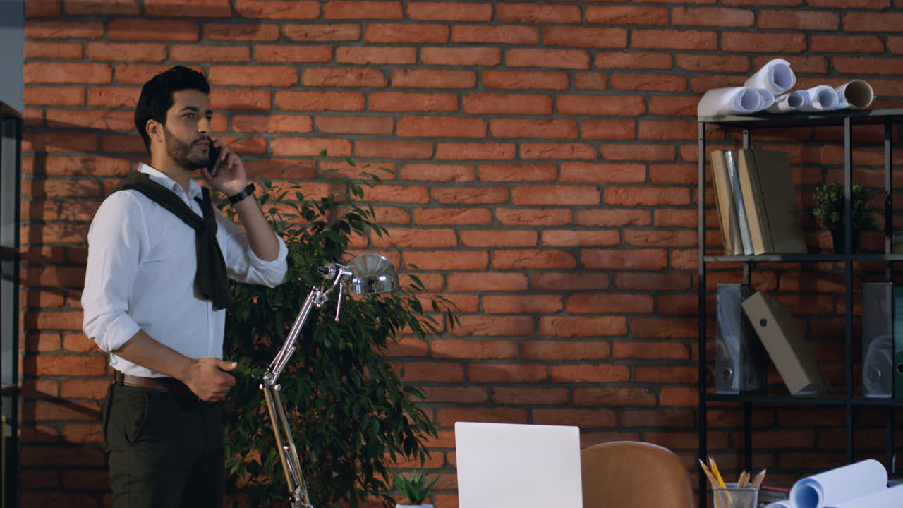 Young Arabian Businessman Walking In The Modern Office Room, Talking On The Phone And Gesticulating