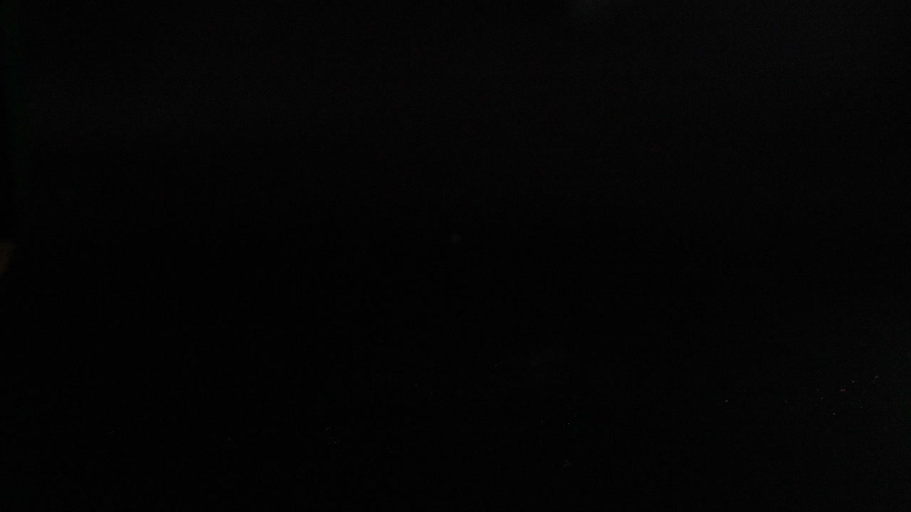 Multiple colored tennis balls bouncing in darkness
