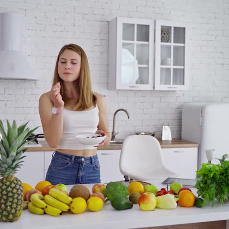 pretty woman in the modern kitchen. organic fruit and vegetables on the table. young woman eating vegan food. healthy diet concept.
