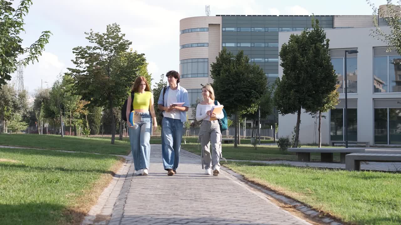 Young friends chatting on university campus footpath