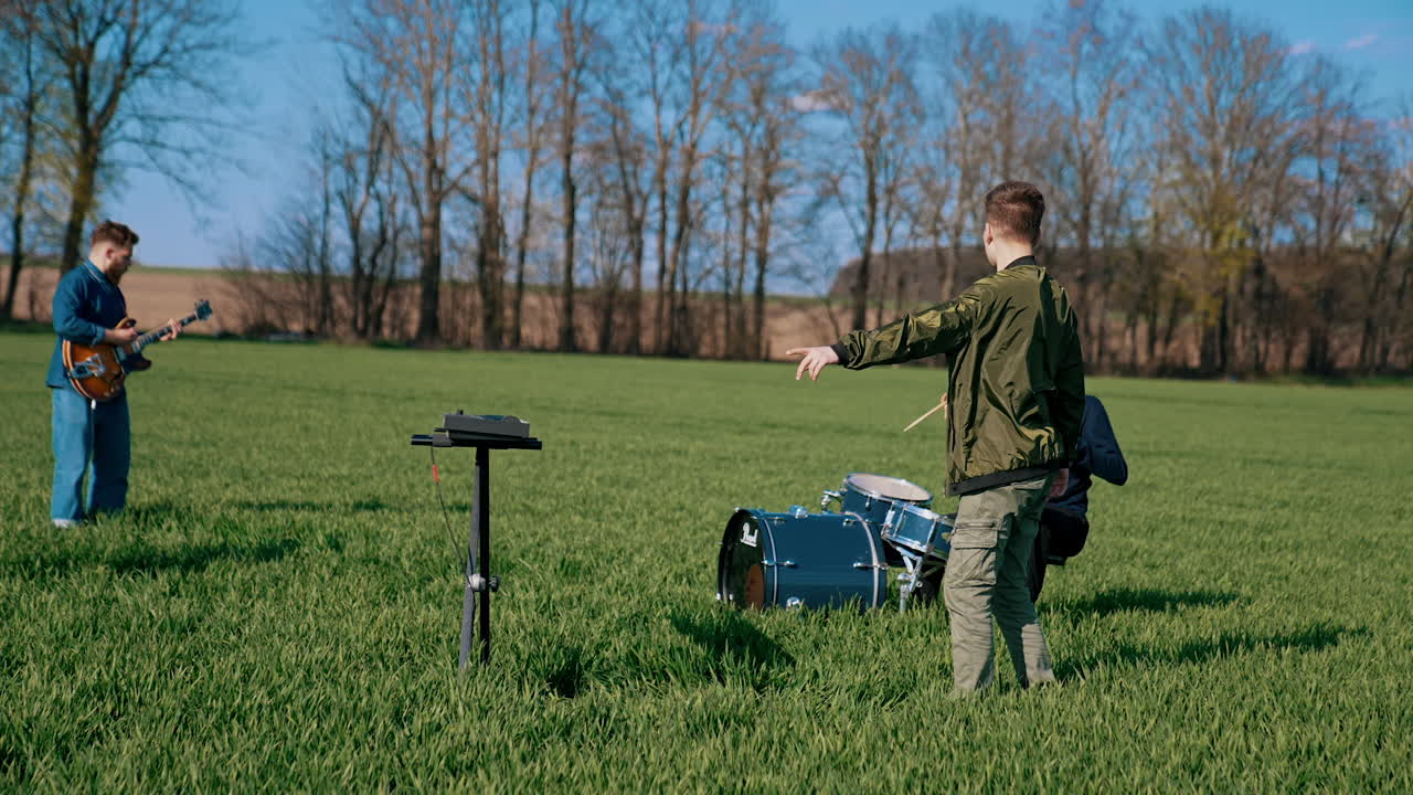 Group playing music outside. Young band play musical instruments on field