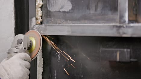 manual cleaning of welded seams with an angle grinder with a flap disc on welded metal construction close-up with long spark trails, slow motion