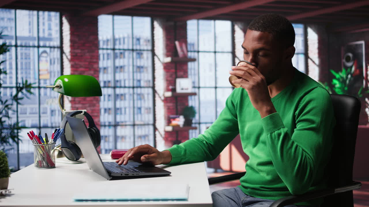 Vertical Video African american adult typing on a computer in his loft apartment