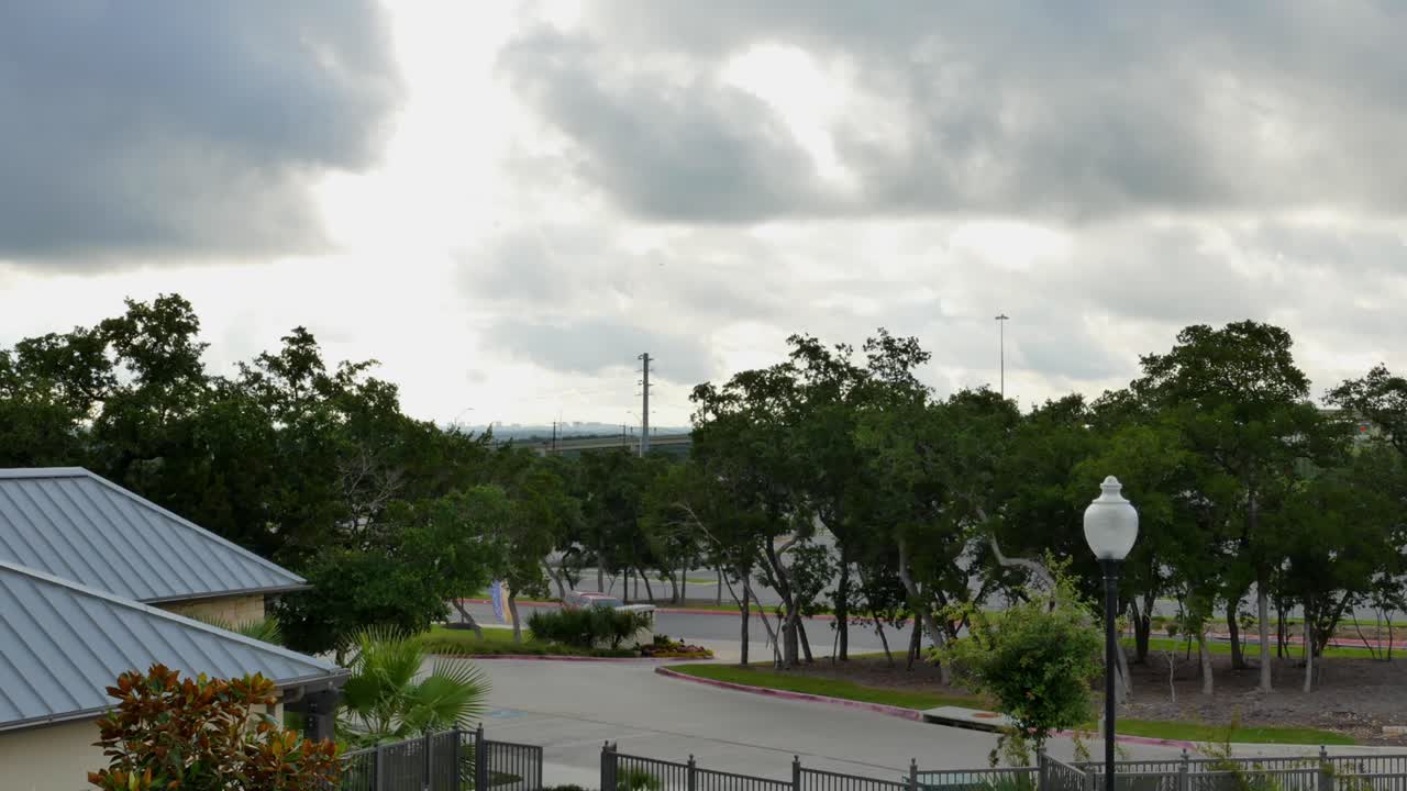 Storm clouds passing over residential area with trees blowing on a grey and stormy day