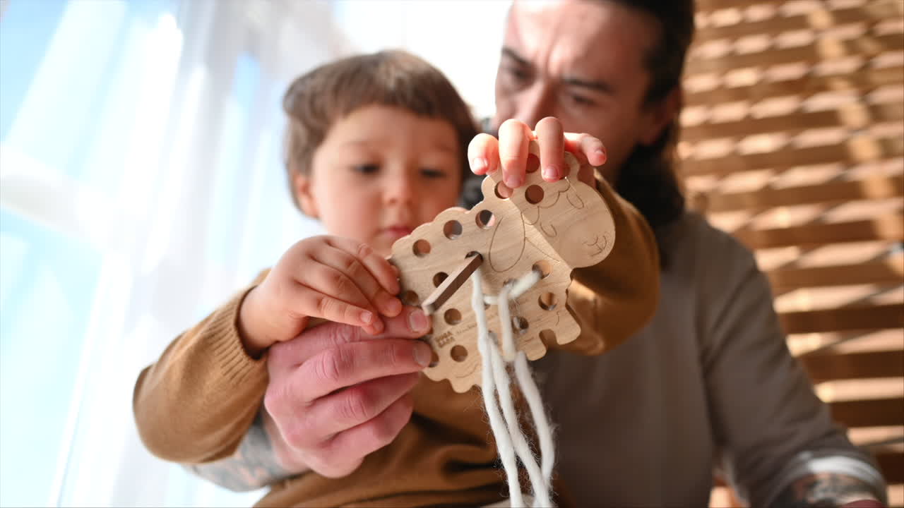 Father playing with his son with ecological wooden toys near the window