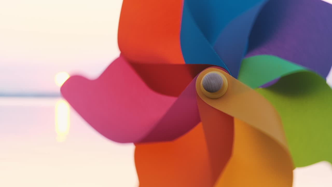 girar rodillo de plástico girar con un viento soplando se encuentra en la arena junto al mar contra la superficie lisa del mar y una puesta de sol rosada brillante molino de juguetes en la playa gran disco del sol espacio de copia