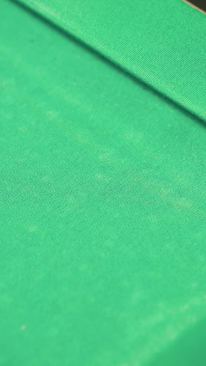 Uma bola de bilhar vermelha rola suavemente para dentro da caçapa de uma mesa de sinuca verde. Um close-up captura a precisão, o momentum e os momentos finais de um lance bem-sucedido, destacando a exatidão e o gameplay.